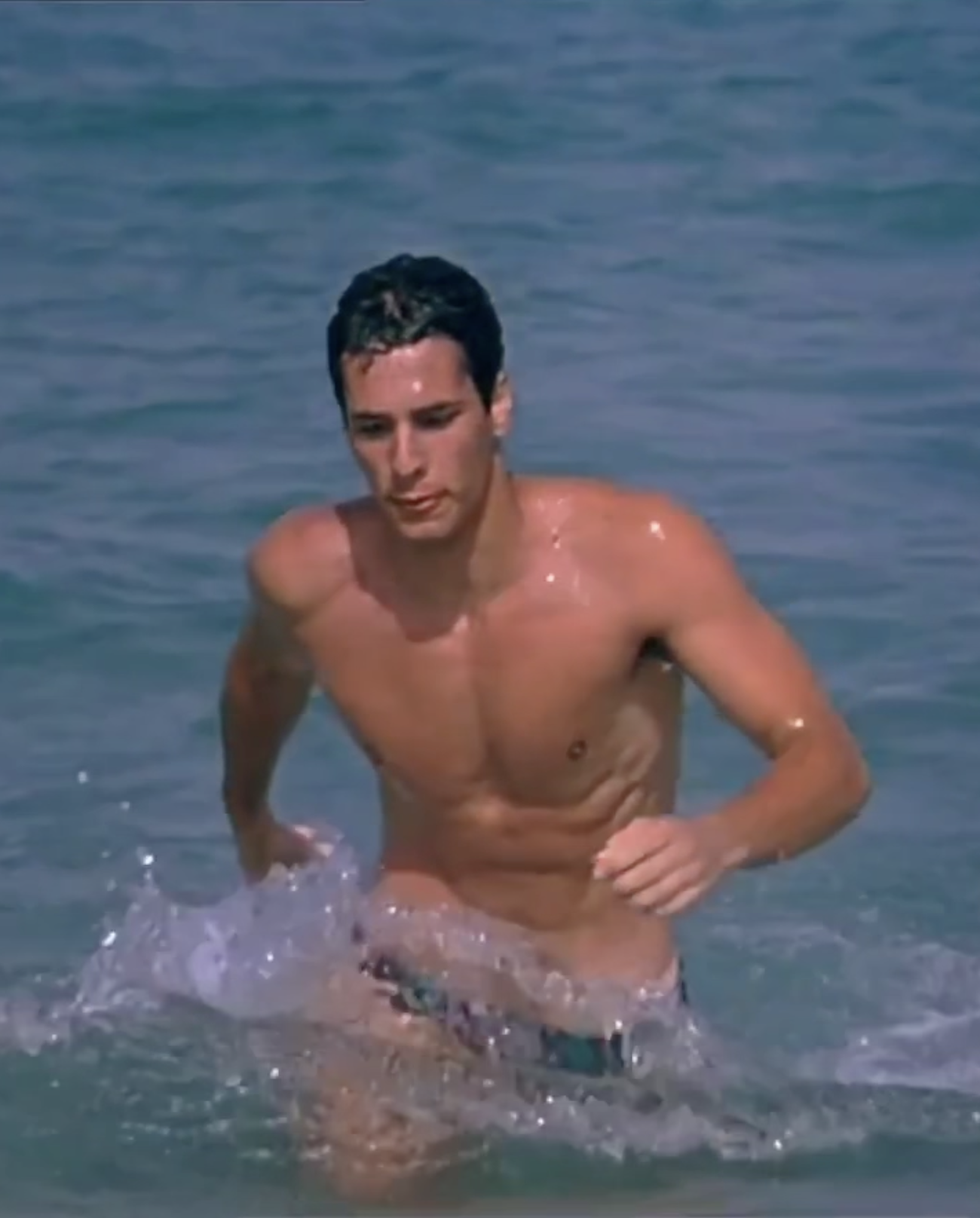 A film still of a man walking from the sea